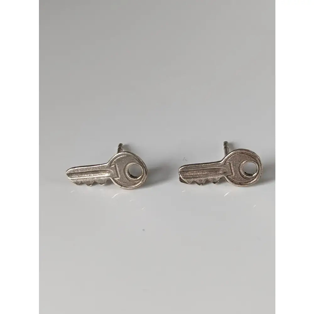 Silver steed key stud earrings featuring polished silver key shaped stud earrings with metallic finish