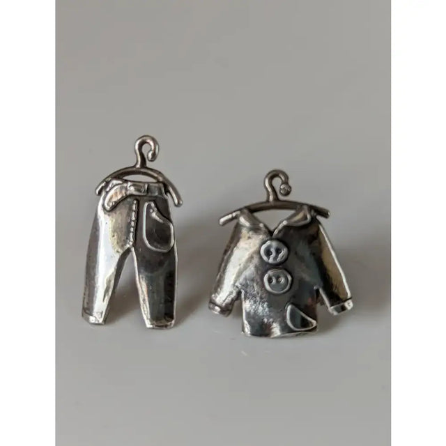 Silver steed pajama stud earrings featuring silver metal charms shaped like jeans and a button-up shirt hanging on hooks