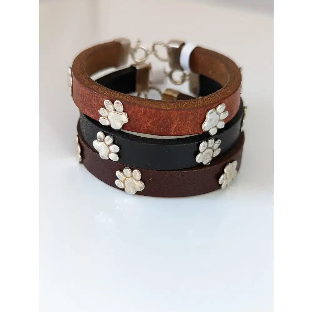 Stacked silver steed paw print leather bracelets in tan black and dark brown with silver charms