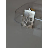 Silver pendant silver steed paw with a textured matte finish and cut out paw print tag design with gold bail