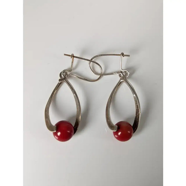 Silver steed red bead dropped earrings feature silver teardrop shapes with vibrant red spherical beads