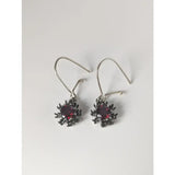 A pair of silver steed red crystal sunflower dropped earrings with dark silver hooks and deep red gemstones