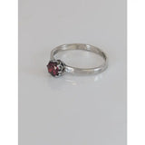A delicate silver steed silver ruby zirconia ring with a single faceted garnet in an ornate prong setting