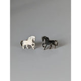 A pair of silver steed running horse stud earrings with one white textured and one solid black horse design
