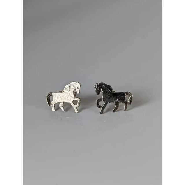 A pair of silver steed running horse stud earrings with one white textured and one solid black horse design