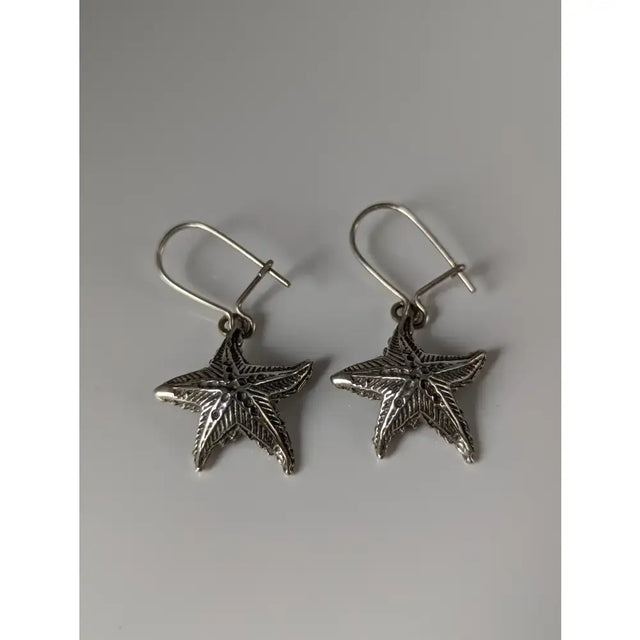Silver steed sea star dropped earrings featuring silver star dropped earrings with textured detailing and hook clasps