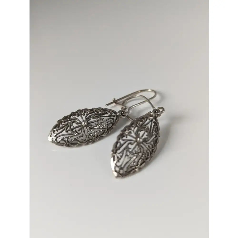 Silver steed shield dropped earrings with intricate floral silver filigree and polished metallic finish