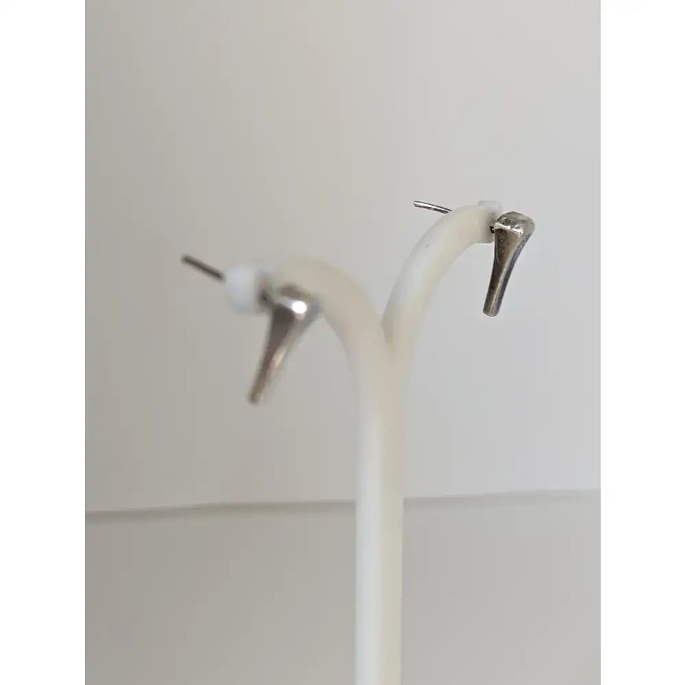 Silver steed short hoof nail stud earrings are silver-toned minimalist studs with pointed design and white accents