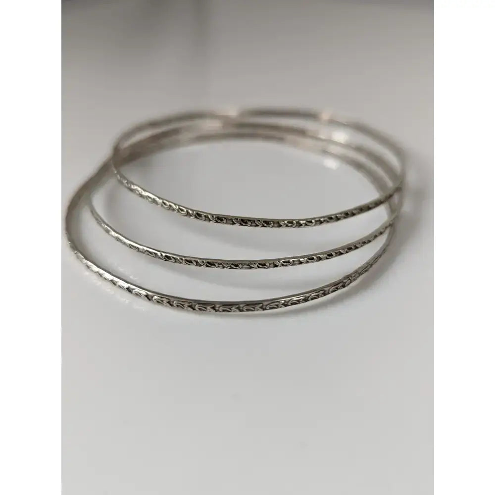 Set of three silver steed slim vine silver bangles with intricate engraved patterns on silver-toned metal