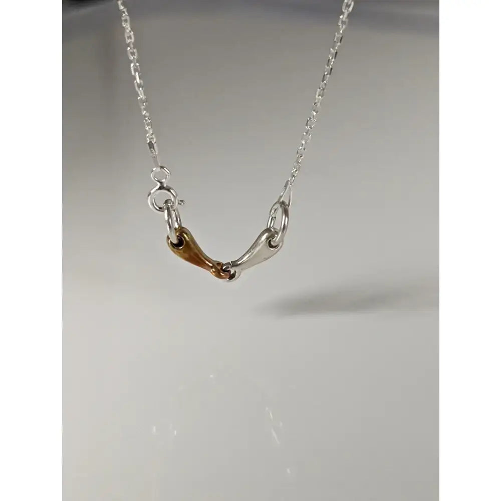 A delicate silver and gold-toned steed snaffle necklace with a fine chain called silver steed snaffle necklace