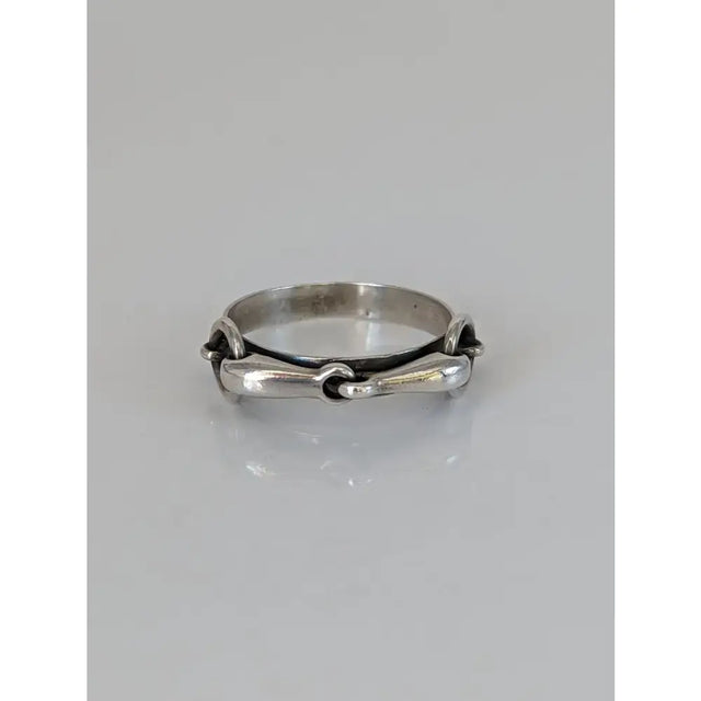 Silver steed snaffle silver horsebit-style ring with polished metallic finish and intricate interlocking design on silver band