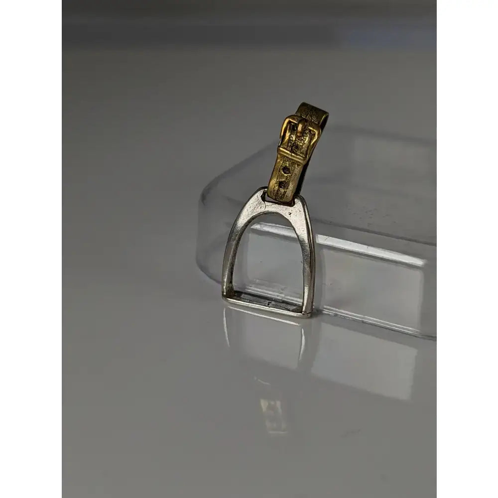 Silver steed stirrup silver pendant featuring a silver horsebit shape with a gold-tone buckle strap detail