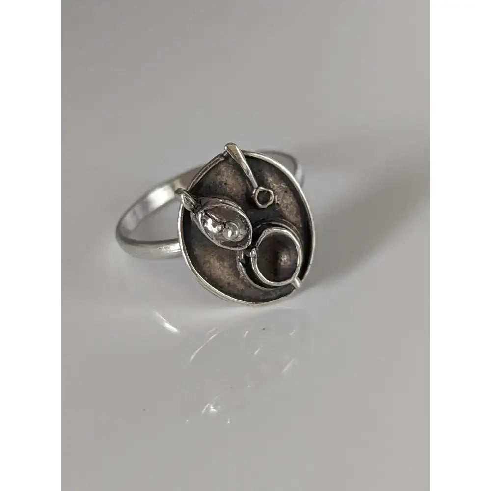 Silver steed tea silver ring with abstract textured face featuring a central oval element and small circular details