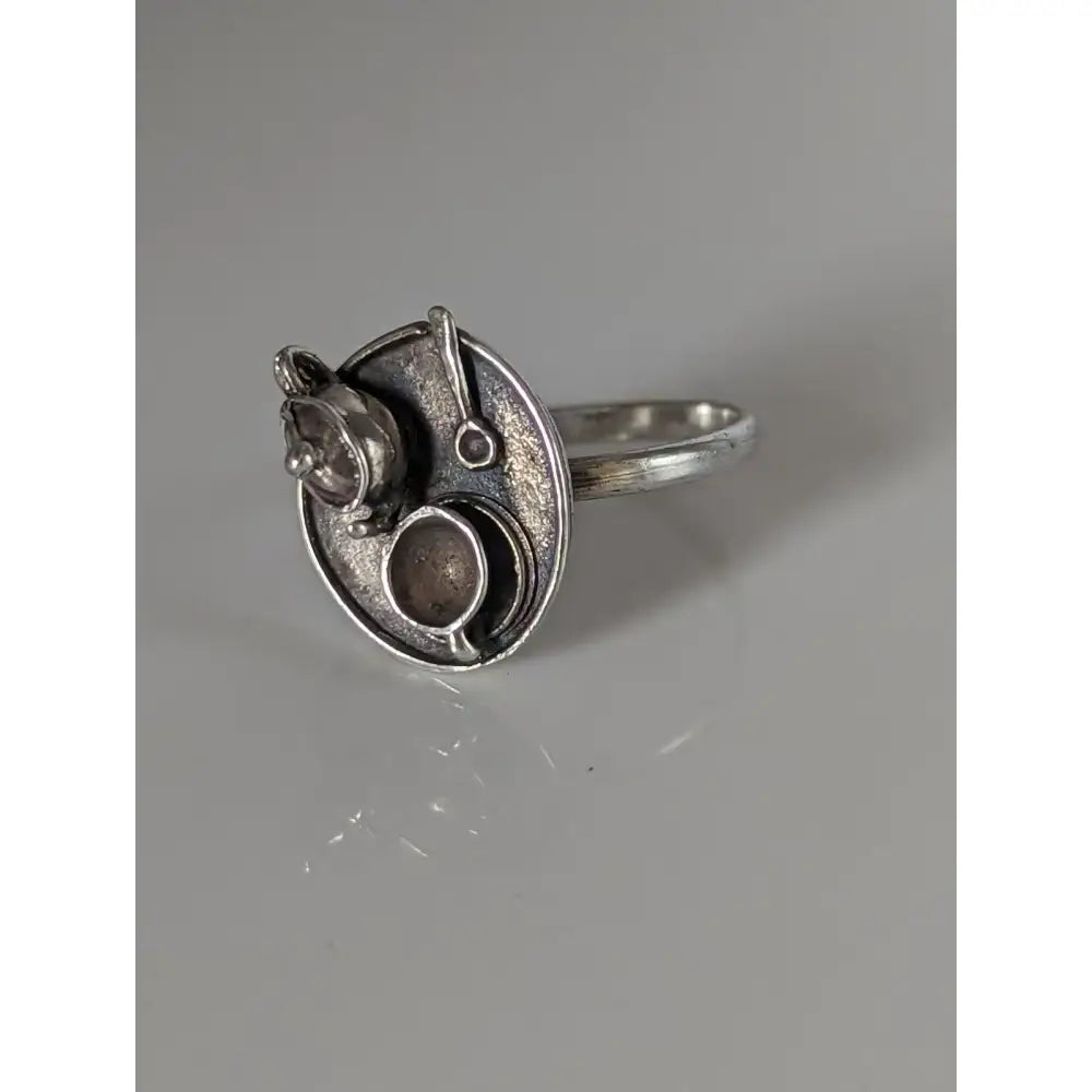 Silver steed tea silver-toned ring with circular textured face and miniature kitchenware sculptures showcasing silver craftsmanship