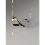 A delicate silver steed two stirrups necklace with gold and silver interlocking stirrup pendants on a fine chain