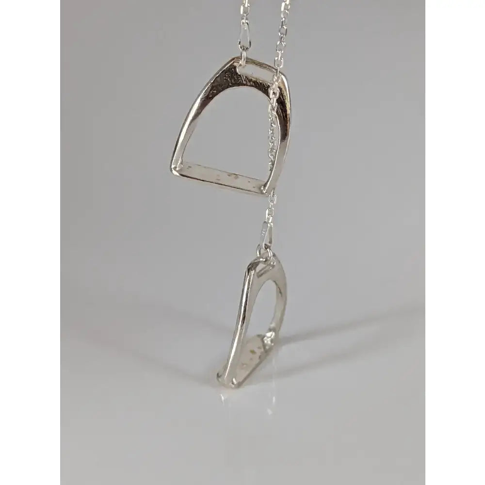 Silver steed equestrian jewelry featuring a silver two stirrups necklace pendant with a textured metallic finish