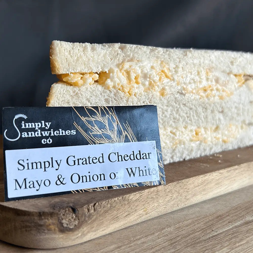 A thick simply sandwiches white bread sandwich filled with grated cheddar cheese mayo and onion perfect with bon sweets pouches
