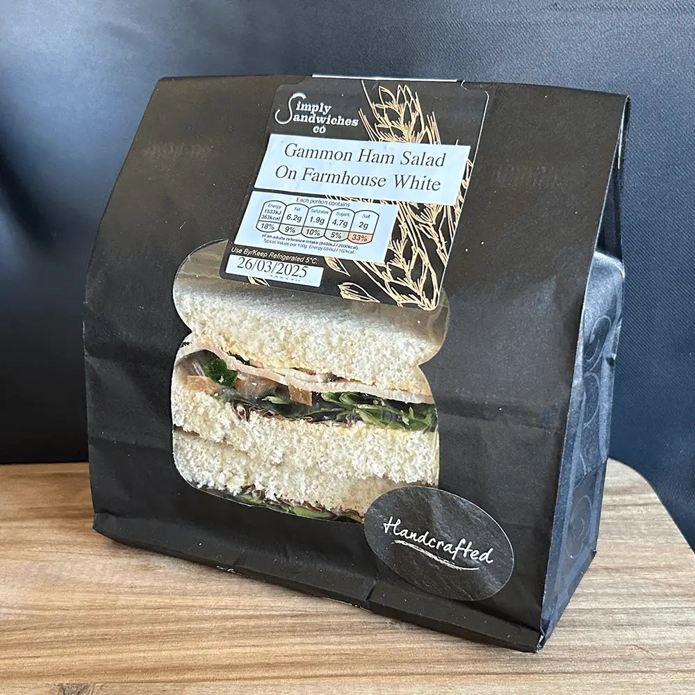 A black paper bag with simply sandwiches gammon ham salad sandwich on farmhouse white bread for lunch or snack