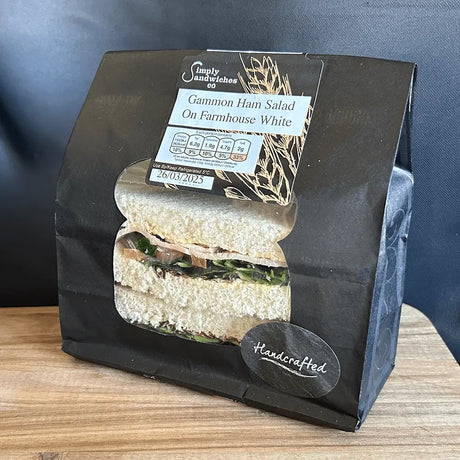 A black paper bag with simply sandwiches gammon ham salad sandwich on farmhouse white bread for lunch or snack