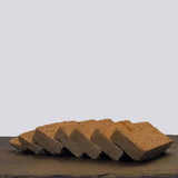 Slices of beige textured tofu arranged on dark surface for skinners field and trail adult chicken root veg wet dog food
