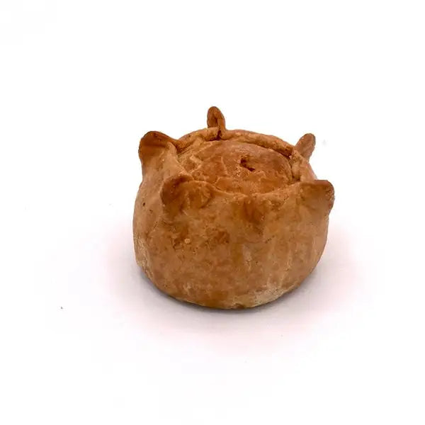 Small hand raised squealer pork pie with golden brown flaky pastry and uneven surface with small raised edges