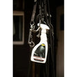 White spray bottle of smart grooming leather care spray with black and yellow label hanging among horse tack