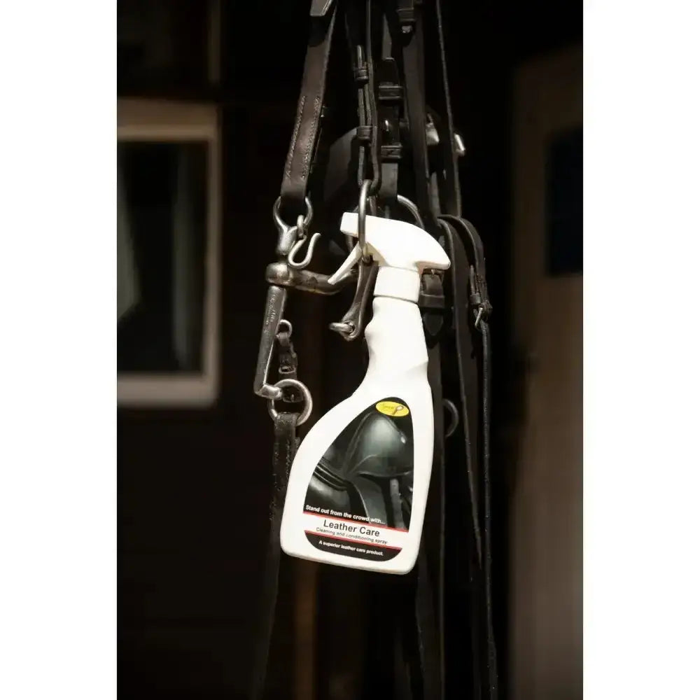 White spray bottle of smart grooming leather care spray with black and yellow label hanging among horse tack