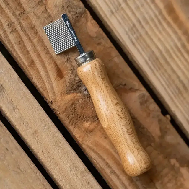 A smart grooming quarter marking comb with a polished wooden handle and metallic finely toothed head made in england