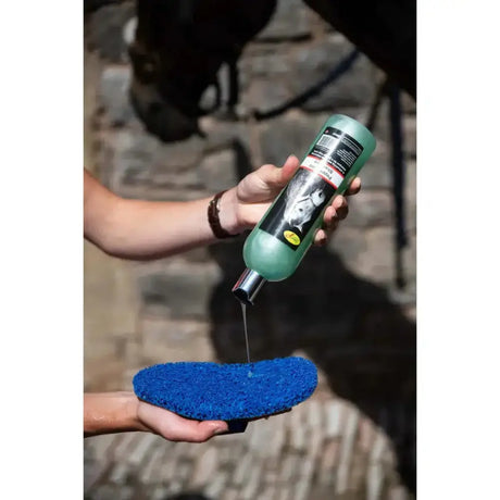 A translucent green bottle with a black label and silver cap holding smart grooming super groomer deluxe horse shampoo for removing dried caked mud