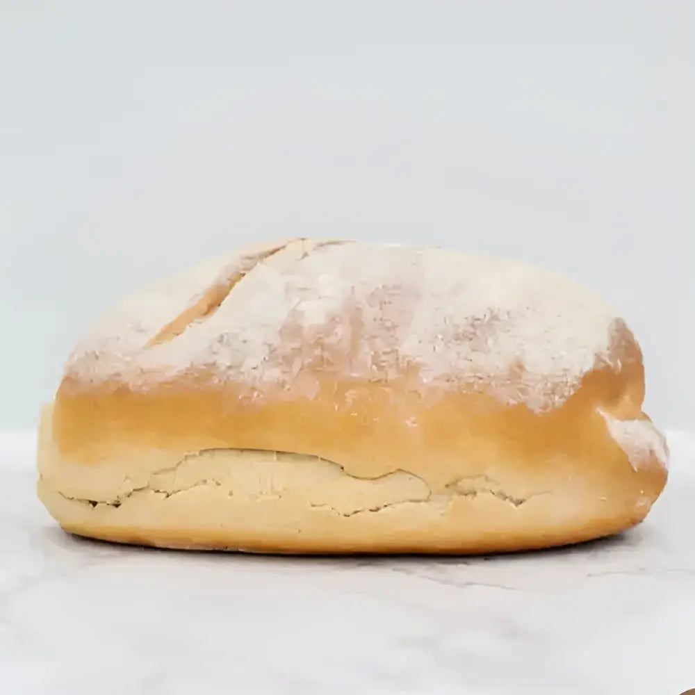 Golden brown sourdough white bread loaf with a scored surface and flour dusting perfect for artisan baking
