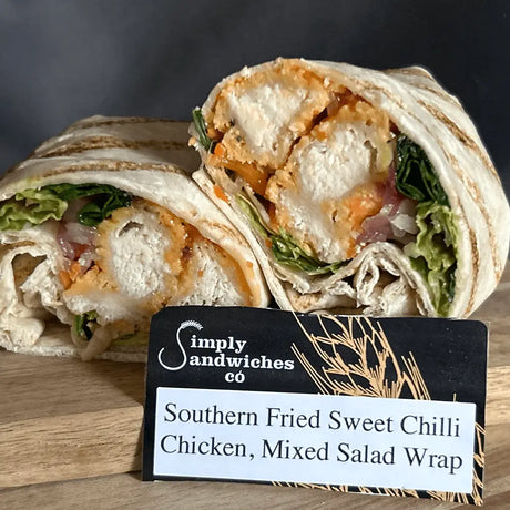 A sliced southern fried sweet chilli chicken mixed salad wrap with crispy chicken and greens in a toasted tortilla