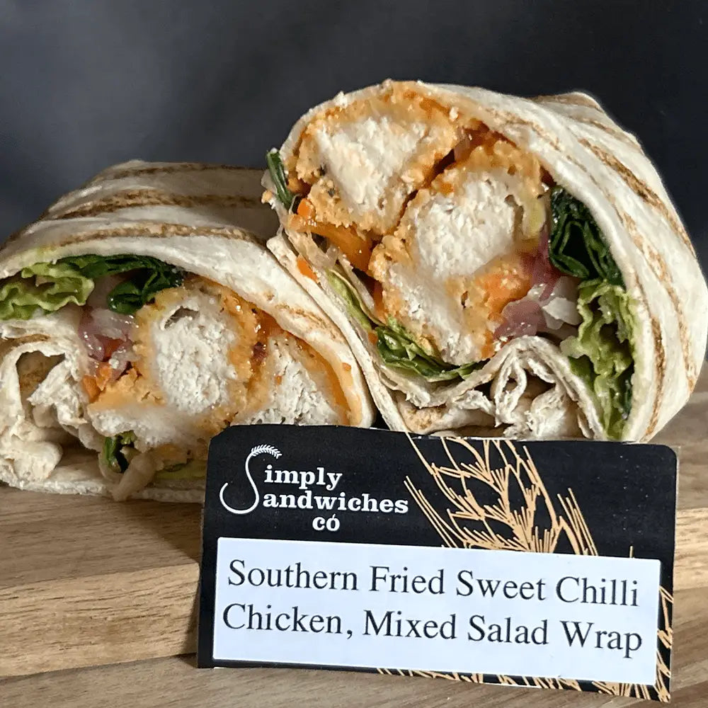 A sliced southern fried sweet chilli chicken mixed salad wrap with crispy chicken and greens in a toasted tortilla