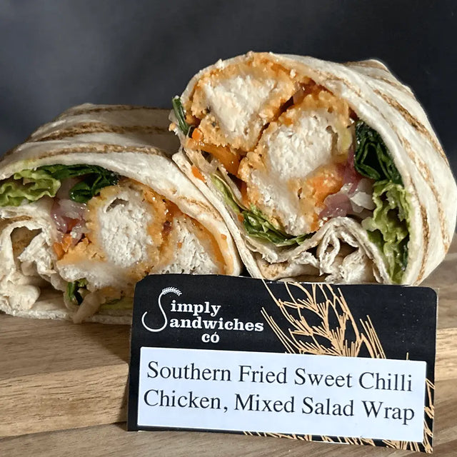 A sliced southern fried sweet chilli chicken mixed salad wrap with crispy chicken and greens in a toasted tortilla