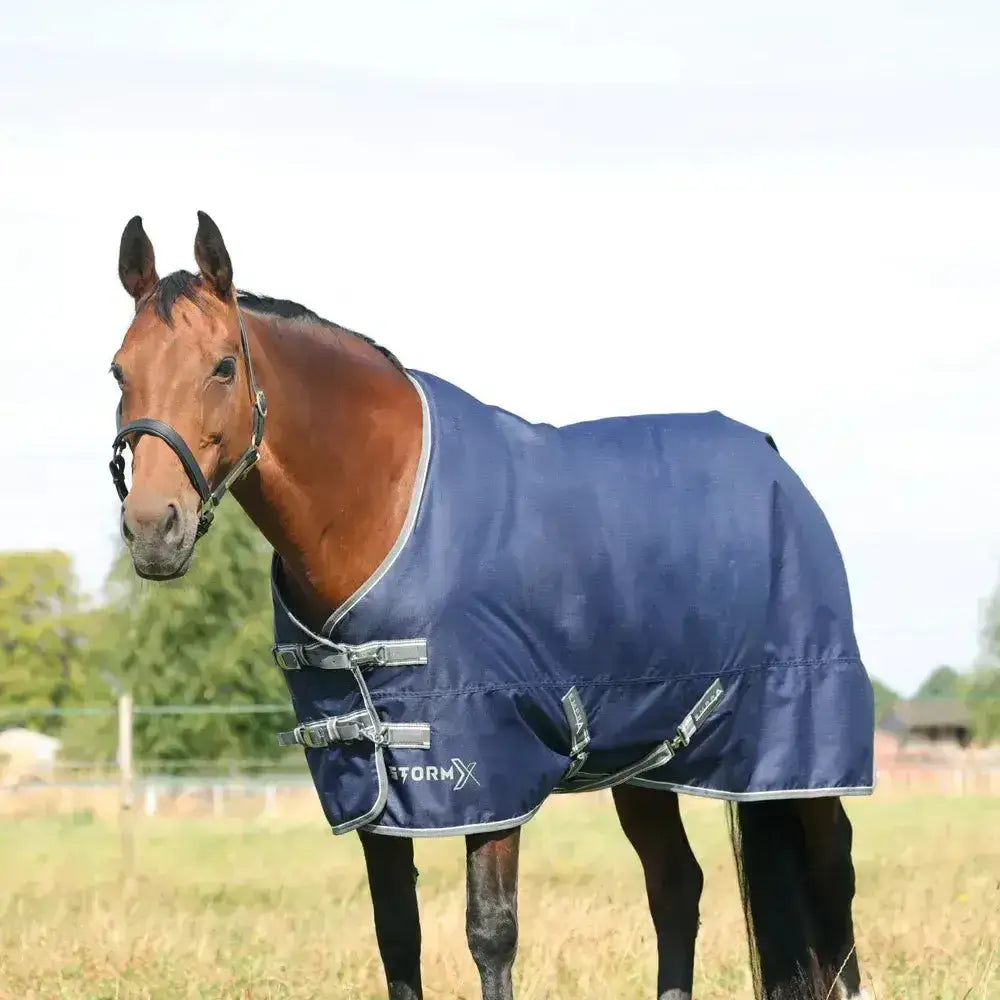 Navy blue stormx empra 100 turnout rug with silver trim and adjustable buckles perfect for equestrian use