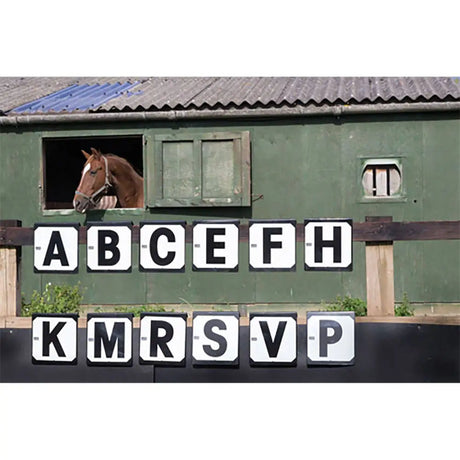 A brown horse with a white blaze looks out a green stable window beside wooden shutters in stubbs hook-on dressage letters markers 12