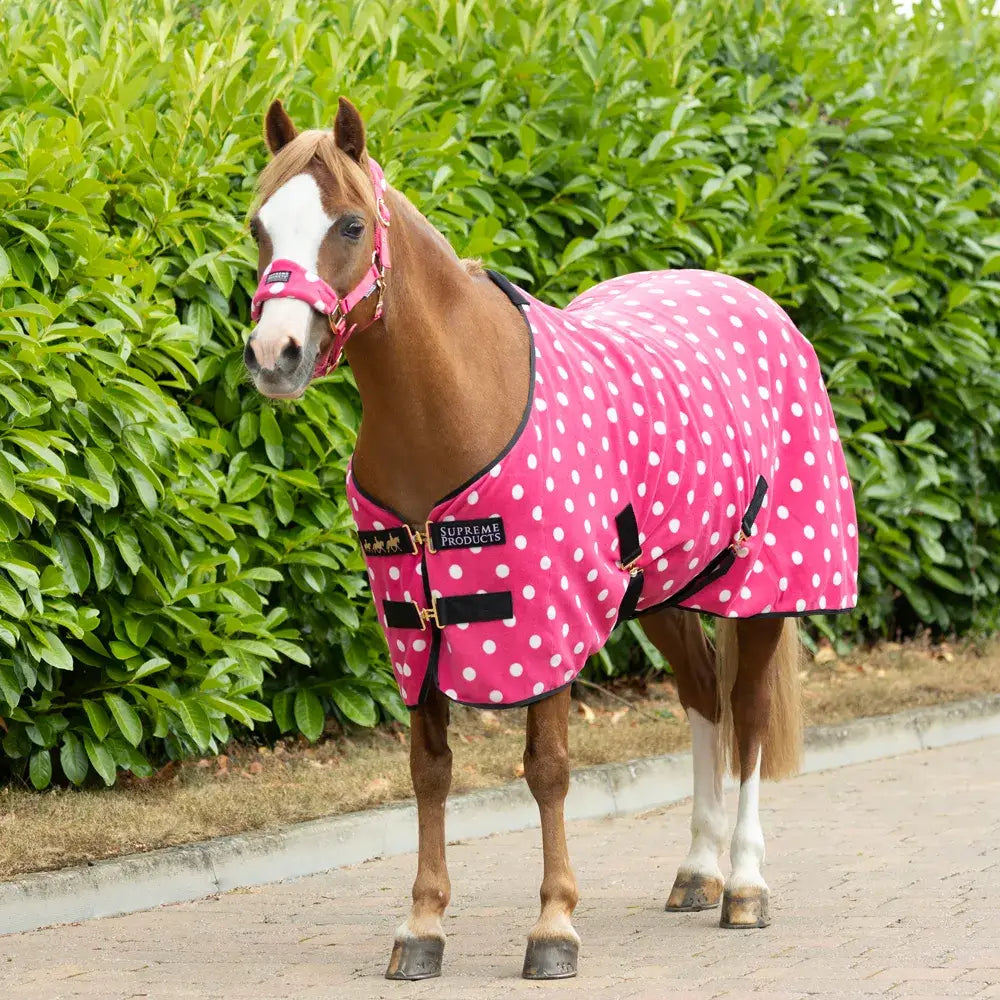Pink polka-dot supreme products dotty fleece rug with black trim and buckle closures made from versatile soft fleece