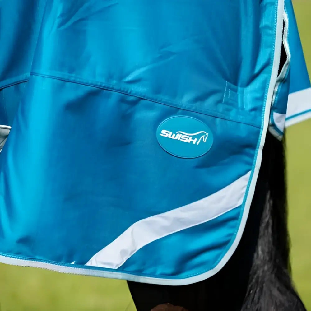 Bright blue swish 100g detachable neck turnout rug with shiny synthetic fabric white trim and circular logo patch