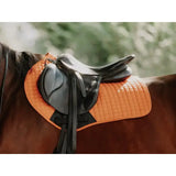 Black leather contact gp saddle resting on saddle pad orange with bright quilted design for high wither support