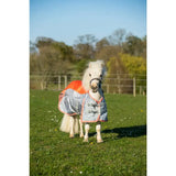 A white pony wearing a swish mini fly turnout combination rug in orange and grey with black buckles