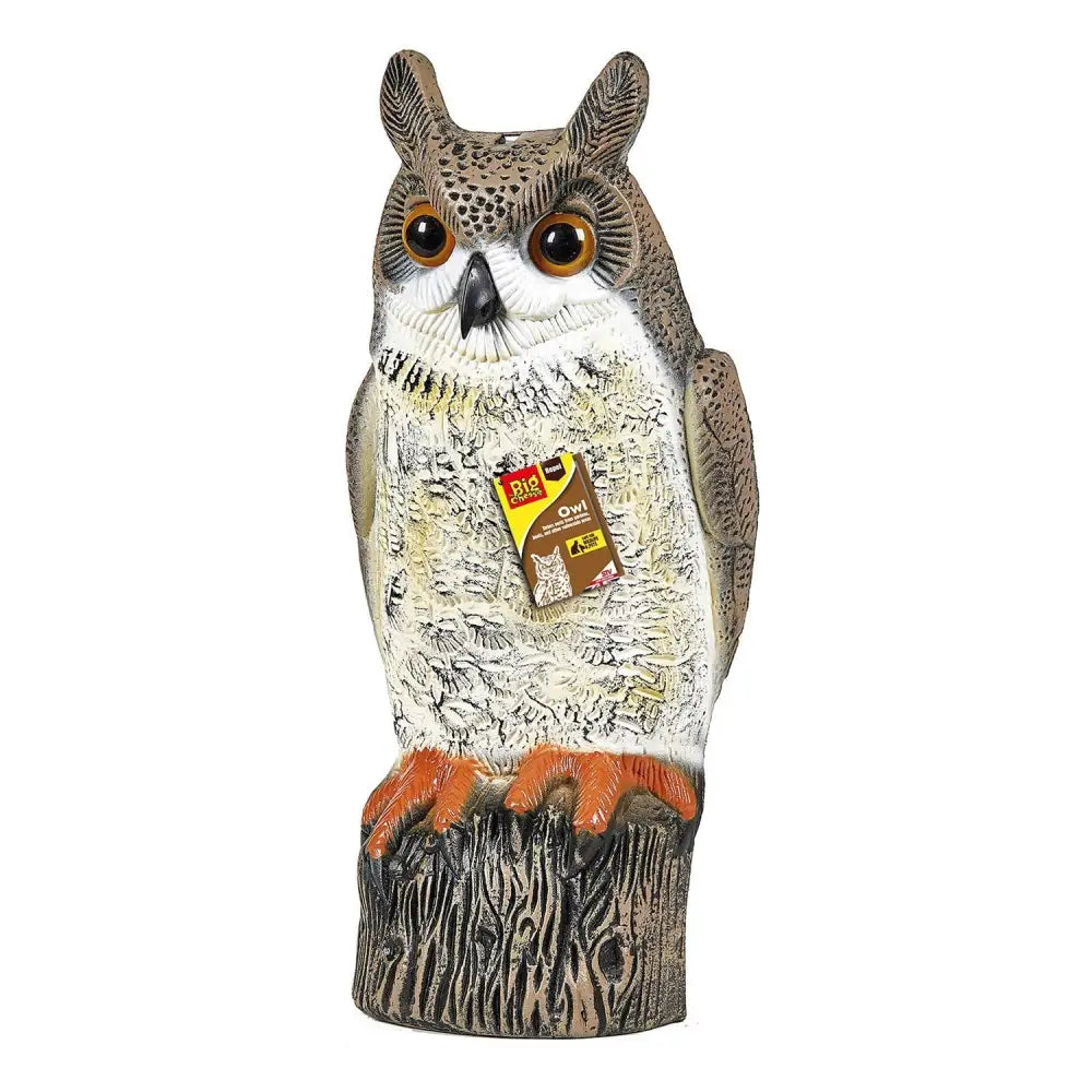 A realistic big cheese owl decoy with detailed brown and white feathers and orange talons on a tree stump base
