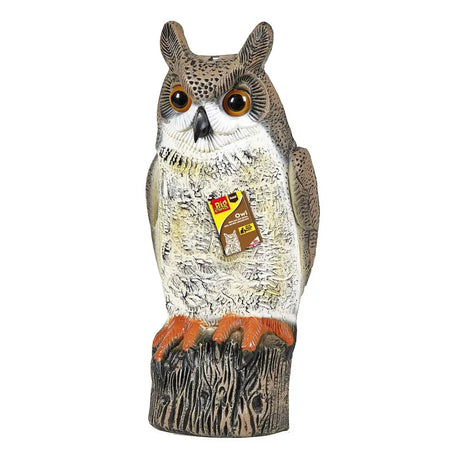 A realistic big cheese owl decoy with detailed brown and white feathers and orange talons on a tree stump base