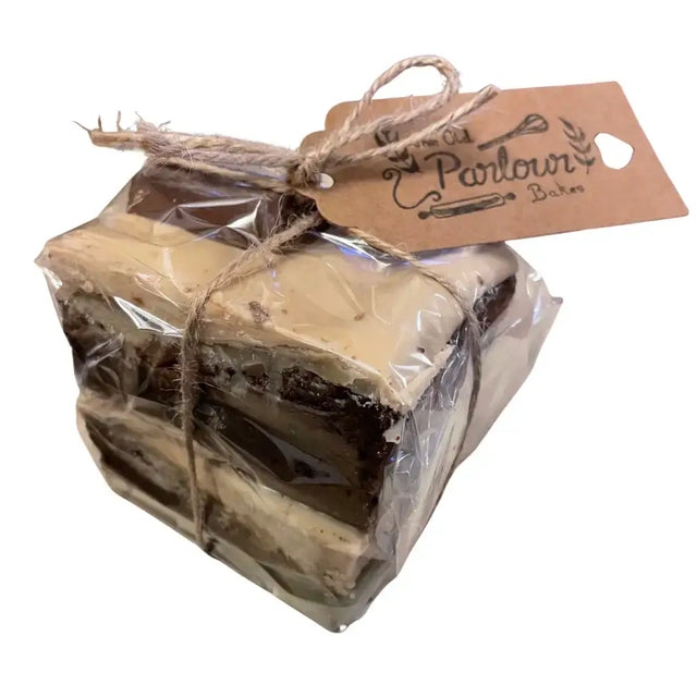 A square layered brownie millionaire slice with gooey chocolate wrapped in clear plastic and twine from parlour bakes