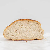 A golden brown crusty tiger bloomer round white bread with a soft airy interior and visible air pockets