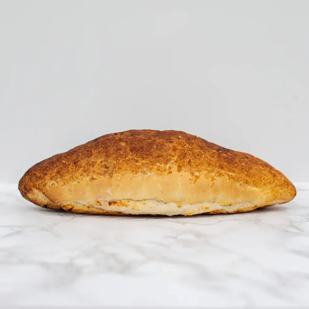 Golden brown tiger bloomer round white bread with flaky rustic crust and visible layers of dough