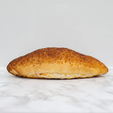 Golden brown tiger bloomer round white bread with flaky rustic crust and visible layers of dough