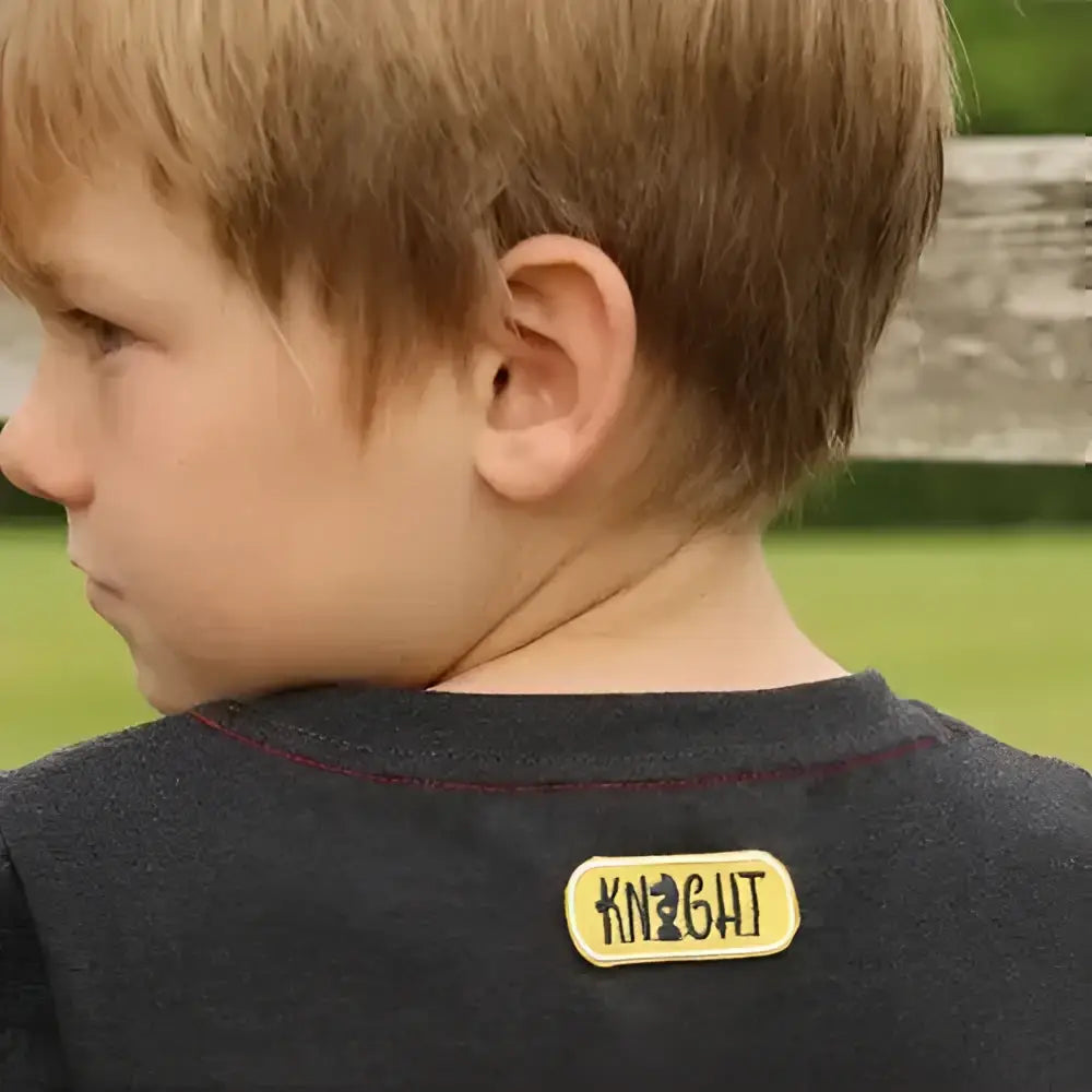 Back of dark gray knit tractor collection t-shirt by little knight with yellow embroidered knight patch and black lettering