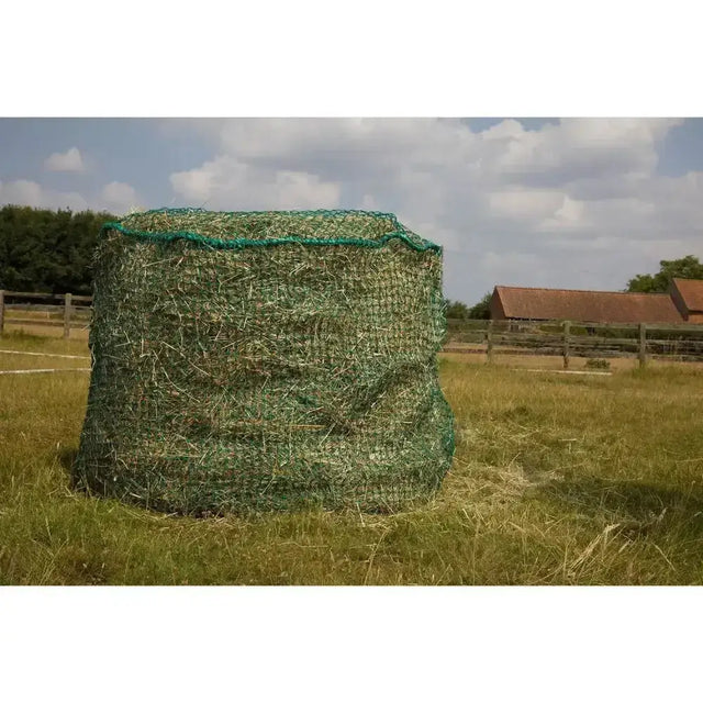 Green mesh trickle net large round bale net covering a hay bale in a grassy field for easy feeding