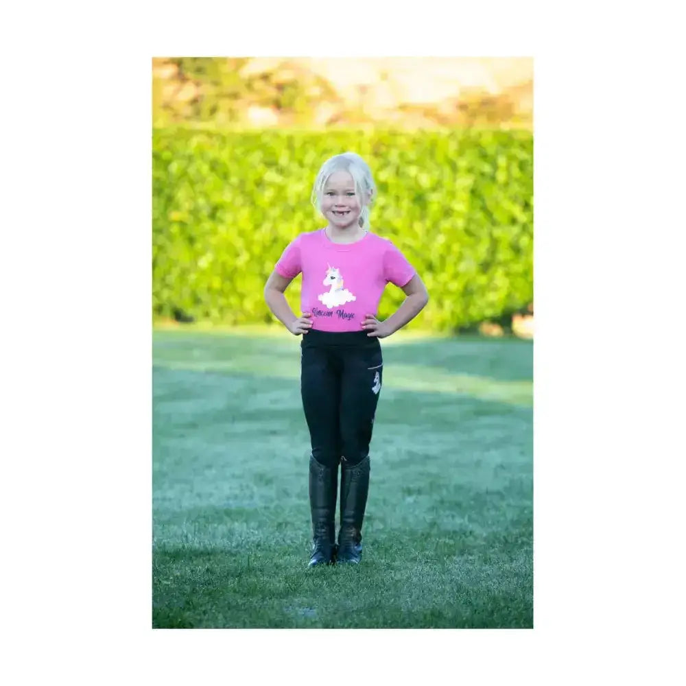 Young girl wearing pink short-sleeved unicorn magic t-shirt by little rider with fun unicorn design and circus magic text