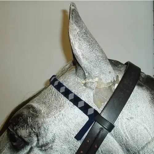 Silver horse head sculpture wearing velvet browbands with a navy white cob argyle patterned strap on black leather bridle