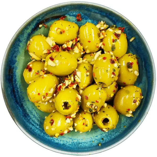 A bowl of vibrant green west country garlic chilli olives halved and seasoned with garlic red pepper flakes and herbs